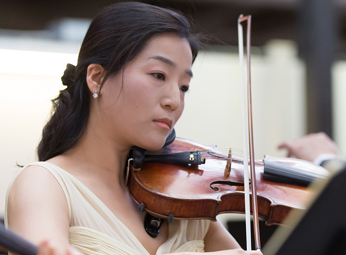 Young woman of Asian descent plays a violin.