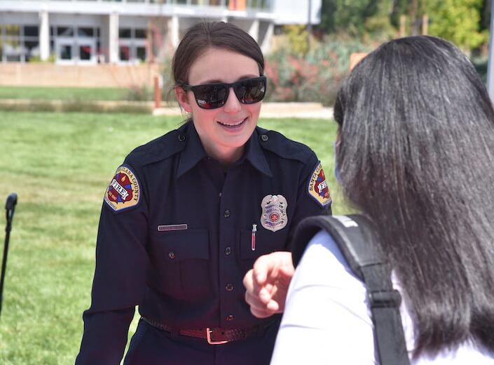 Santa Clara fire department - a young white woman with sunglasses and light brown hair pulled back speaks to a student at the First Responder Fair.
