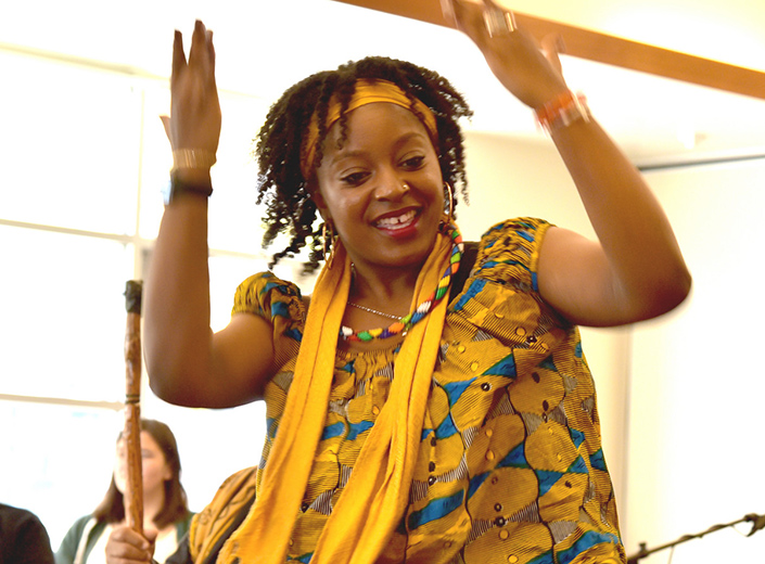 A woman is bright yellow traditional African clothes dances.