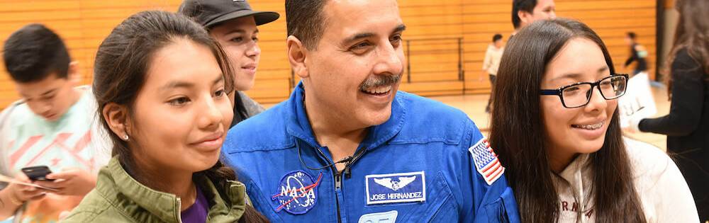 Astronaut Jose Hernandez with two female college students at event.